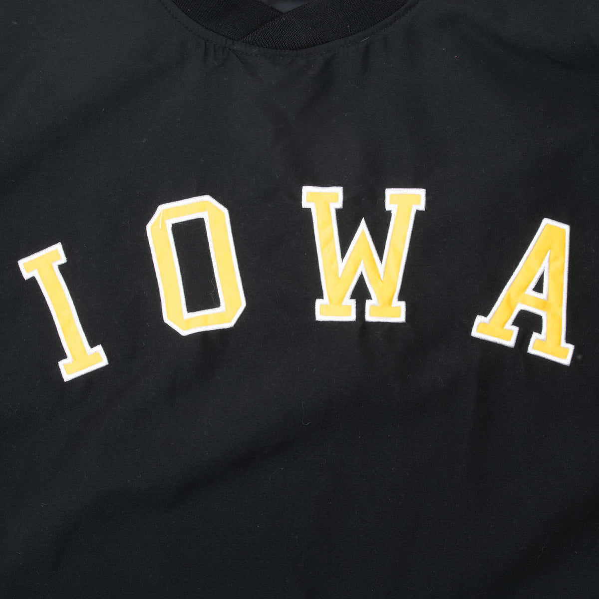 Close-up of gold and white IOWA lettering on black windbreaker chest