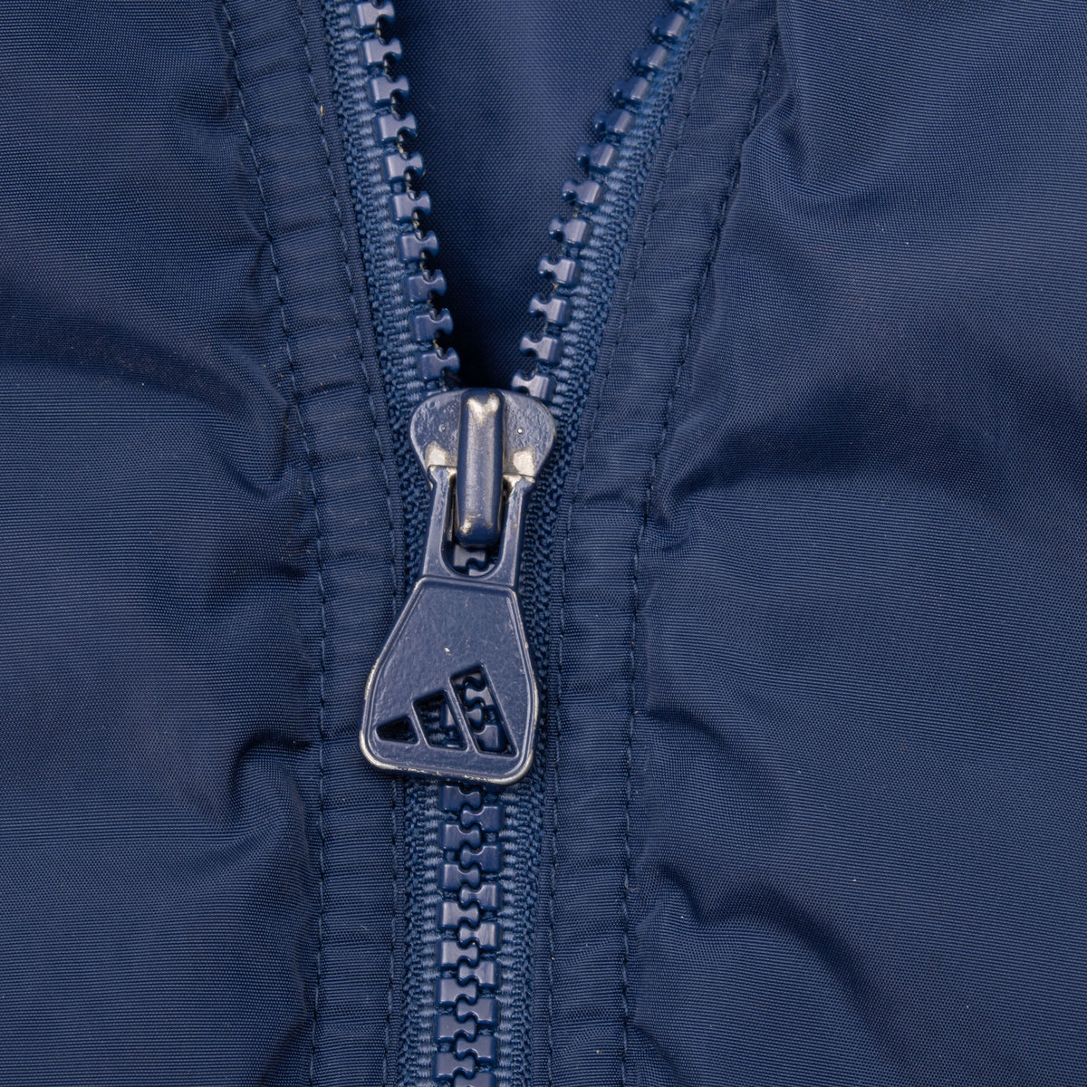 Close-up of blue front zipper with Adidas logo pull