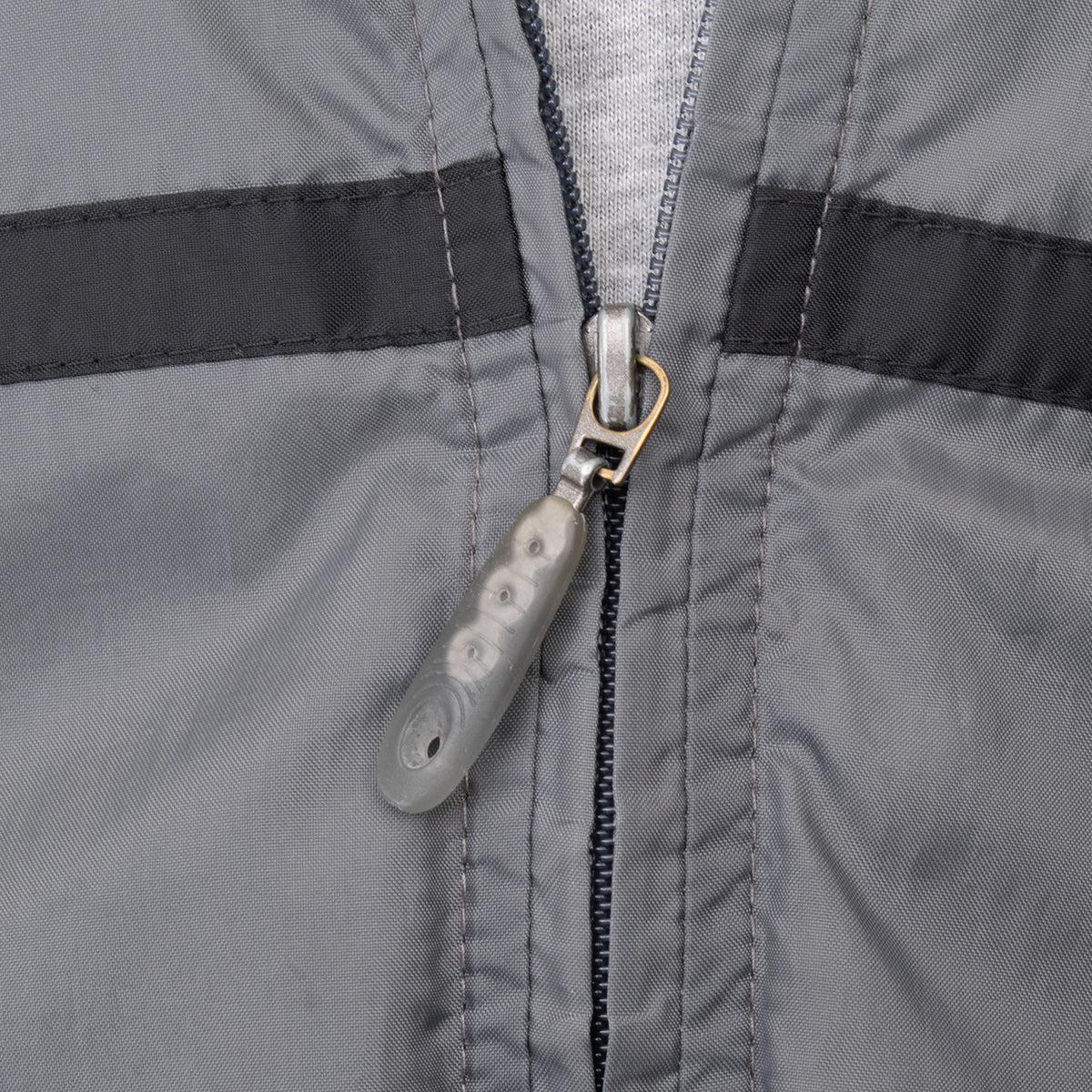 Close-up of front zipper pull and black chest stripe on grey Nike windbreaker