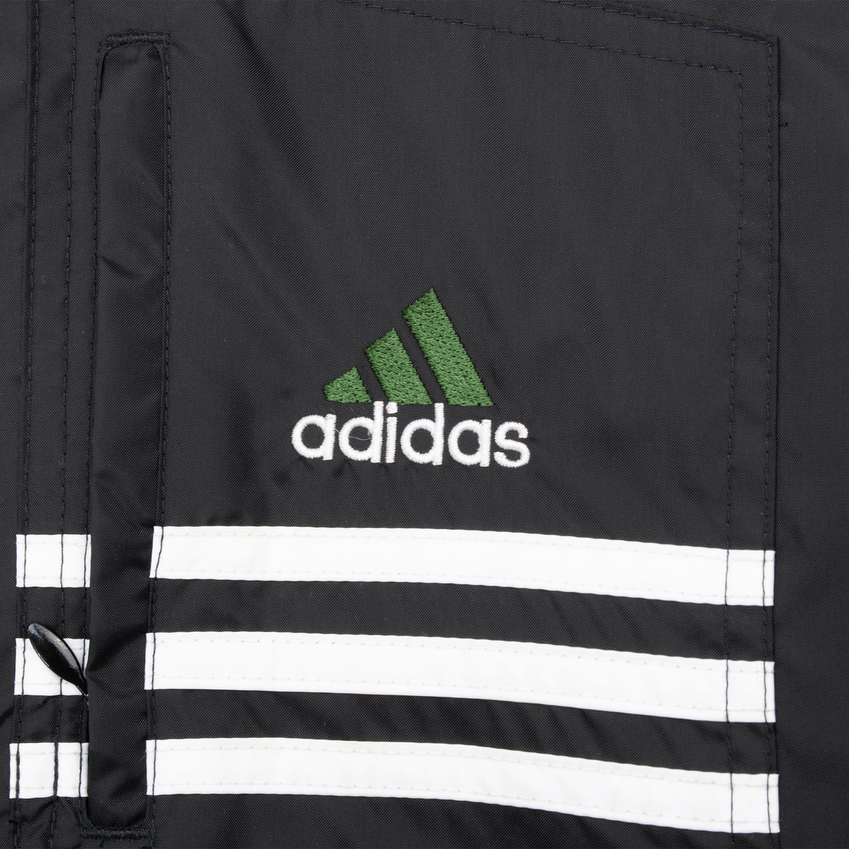 Chest pocket detail with green Adidas logo and three white stripes