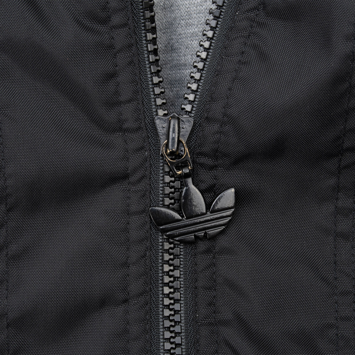 Close-up of black front zipper with Adidas Trefoil pull