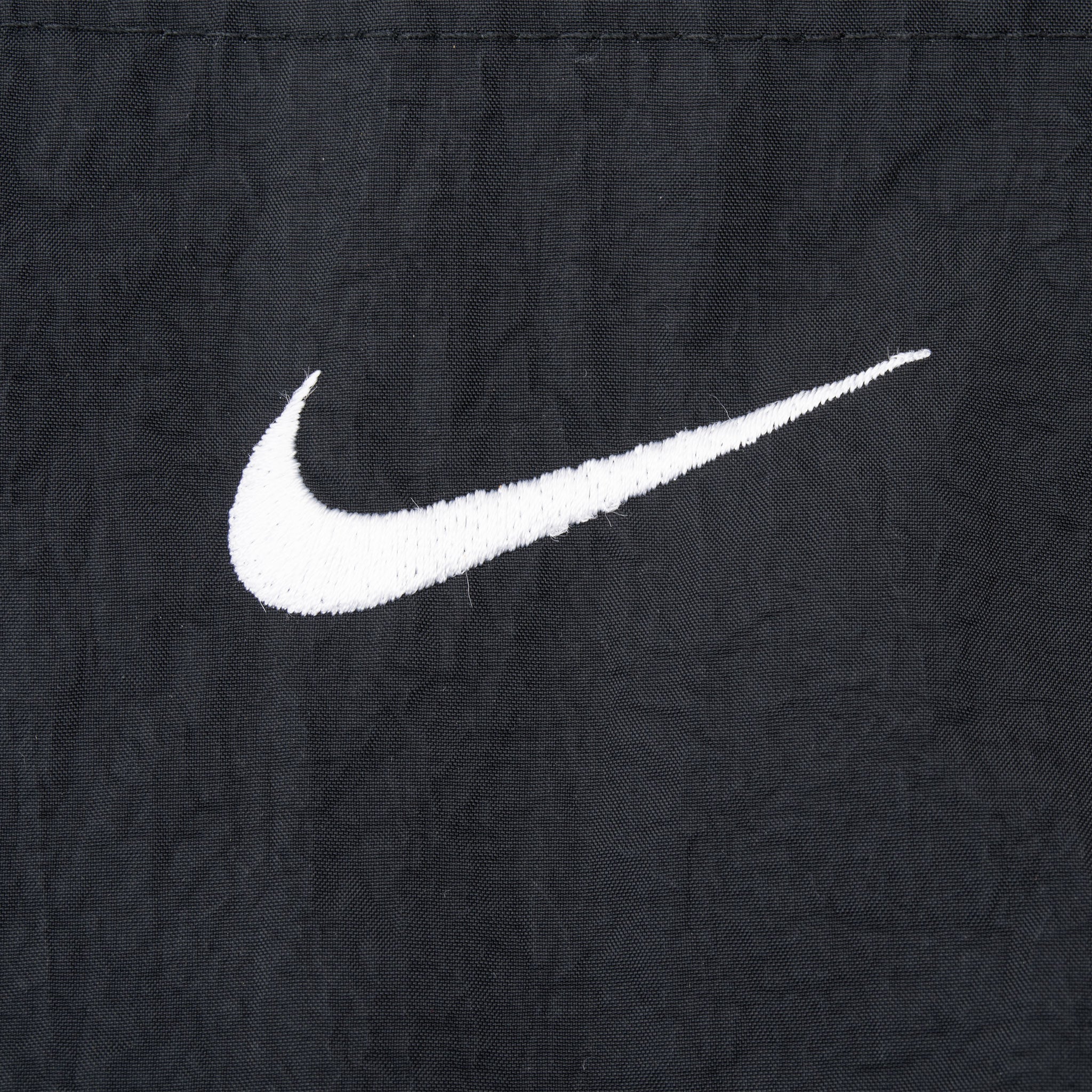 Close-up of white embroidered Nike Swoosh on black fabric
