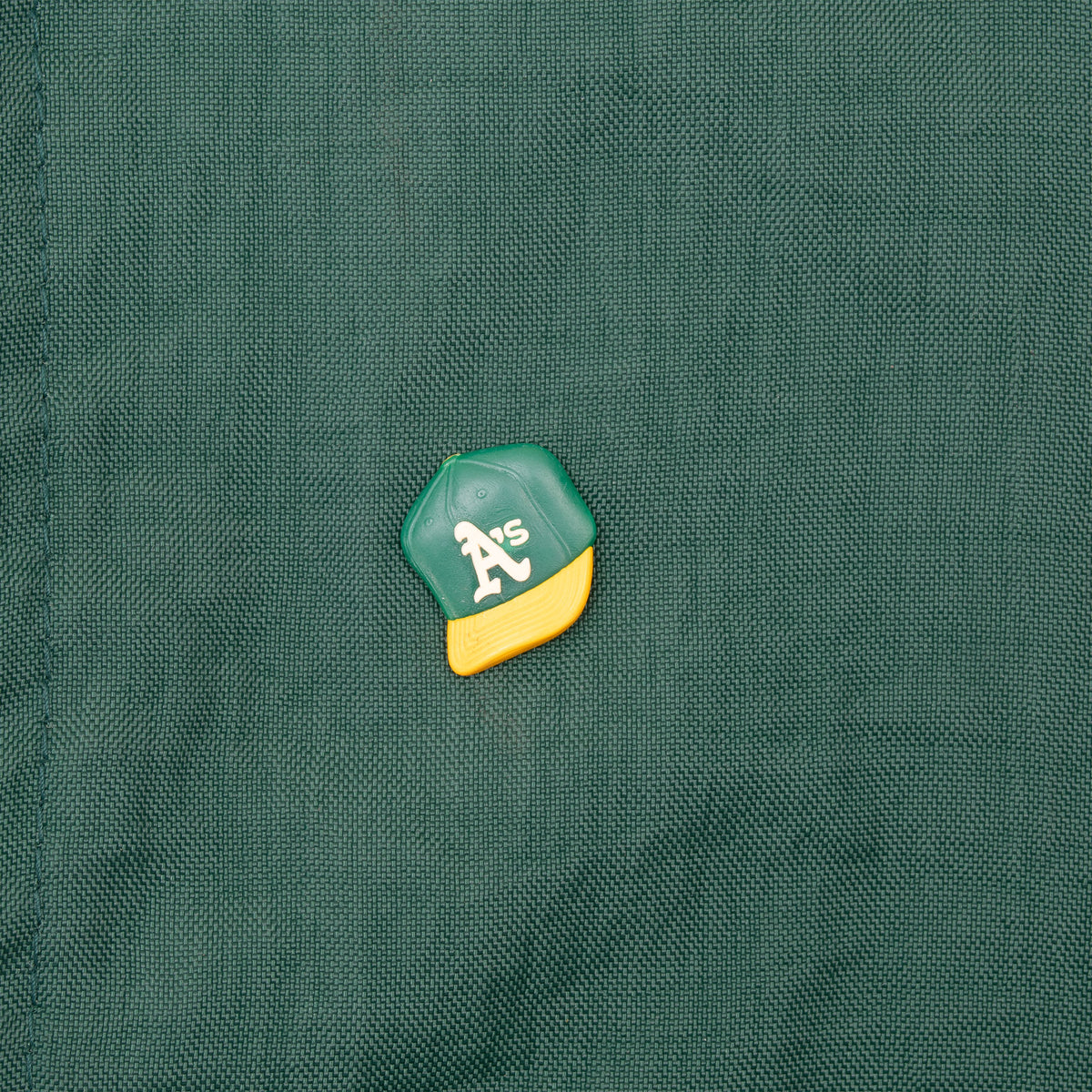 Oakland A's cap-shaped pin detail on green jacket chest