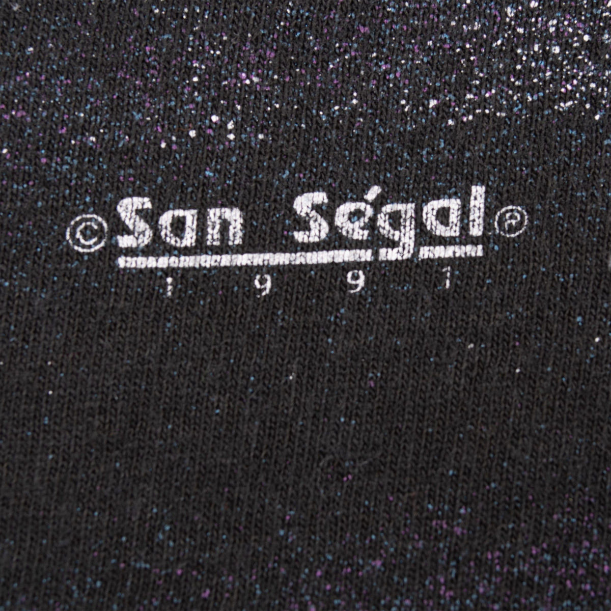 Close-up of San Segal 1991 copyright print on black speckled fabric