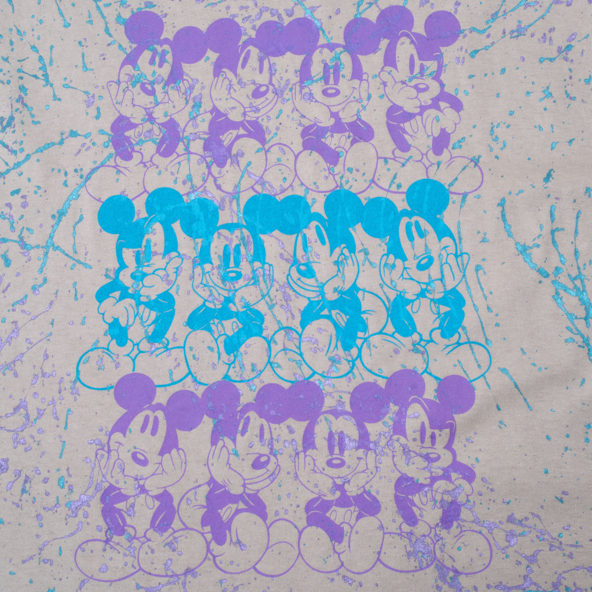 Close-up of blue and purple Mickey Mouse character rows on beige Disney tee