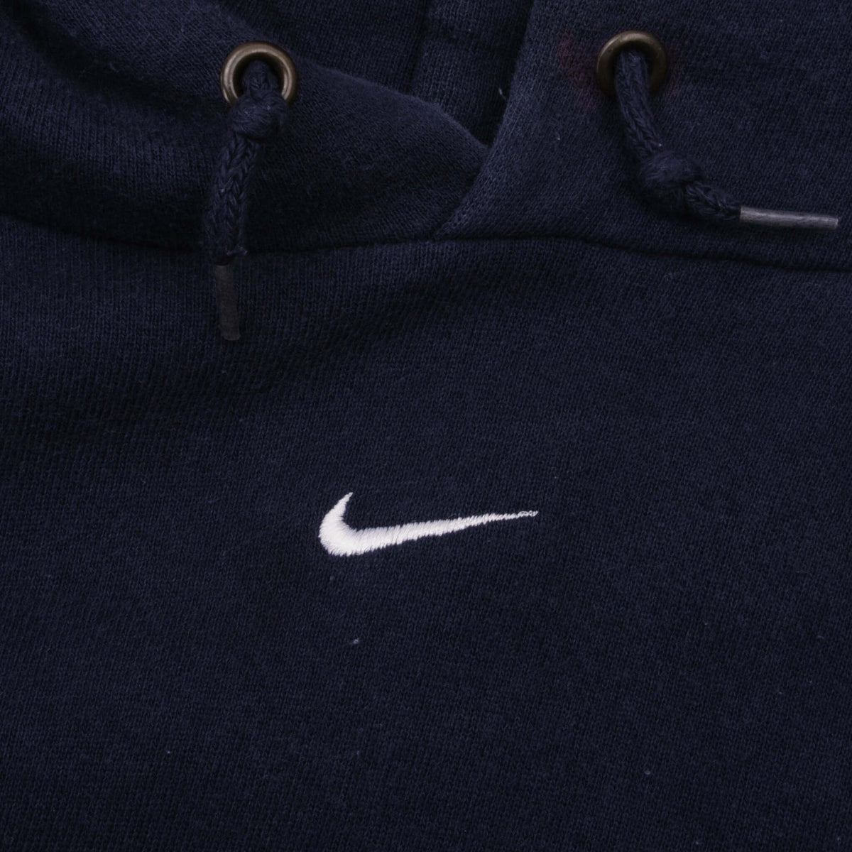 Close-up of white embroidered Nike Swoosh and drawstring hood with metal eyelets