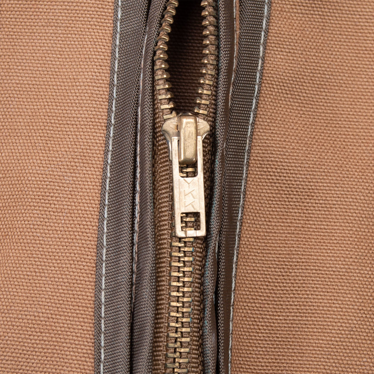 Close-up of metal front zipper and dark contrast trim on brown Carhartt vest