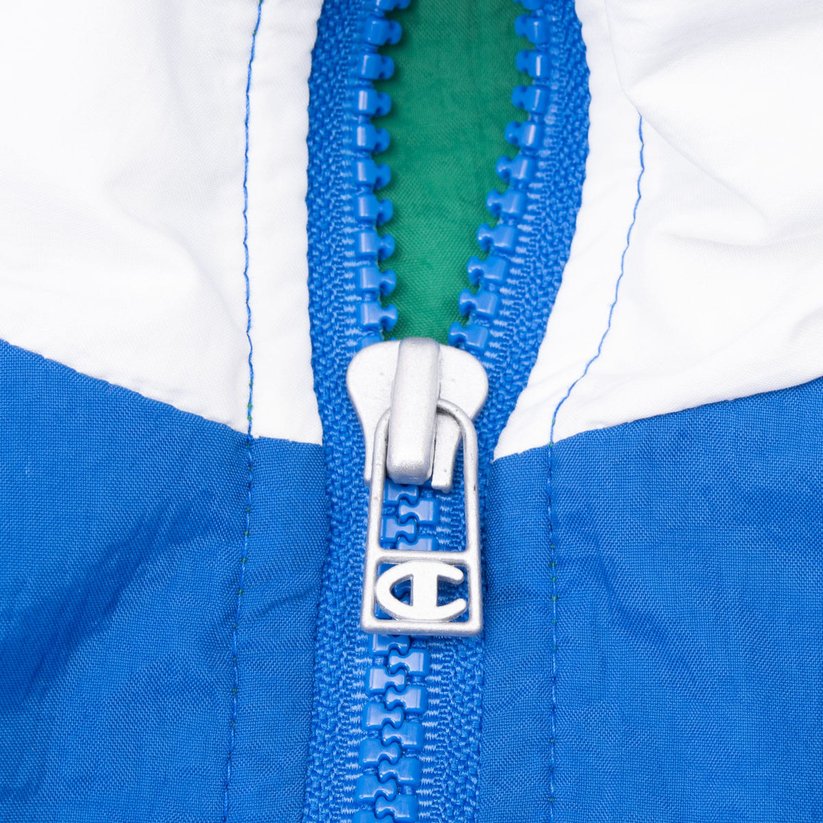 Close-up of blue quarter-zip and Champion C logo zipper pull