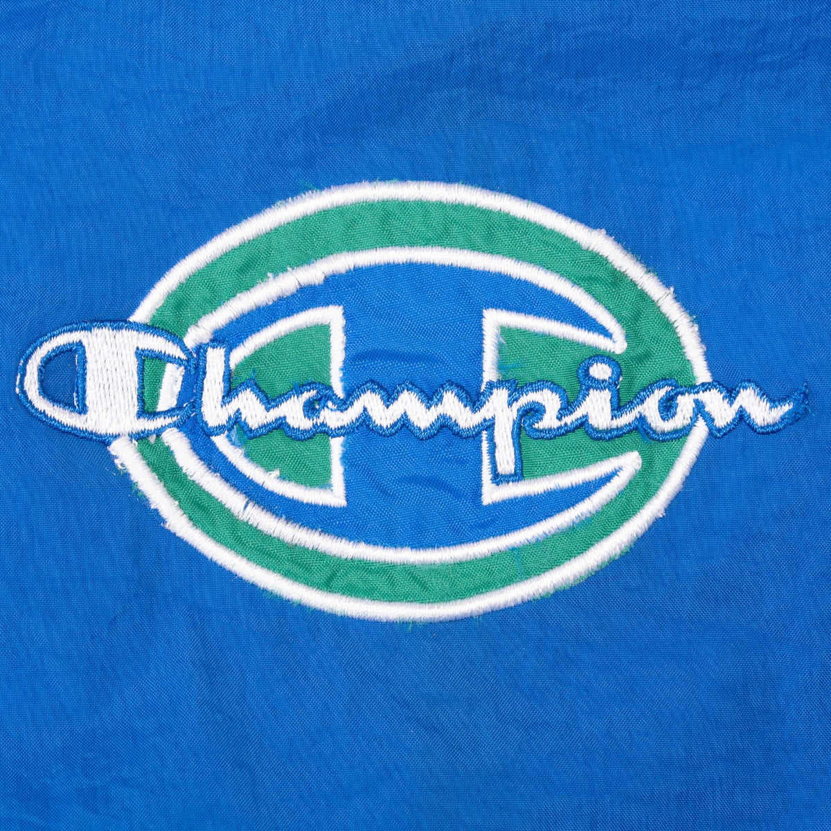 Close-up of blue, green and white Champion chest embroidery