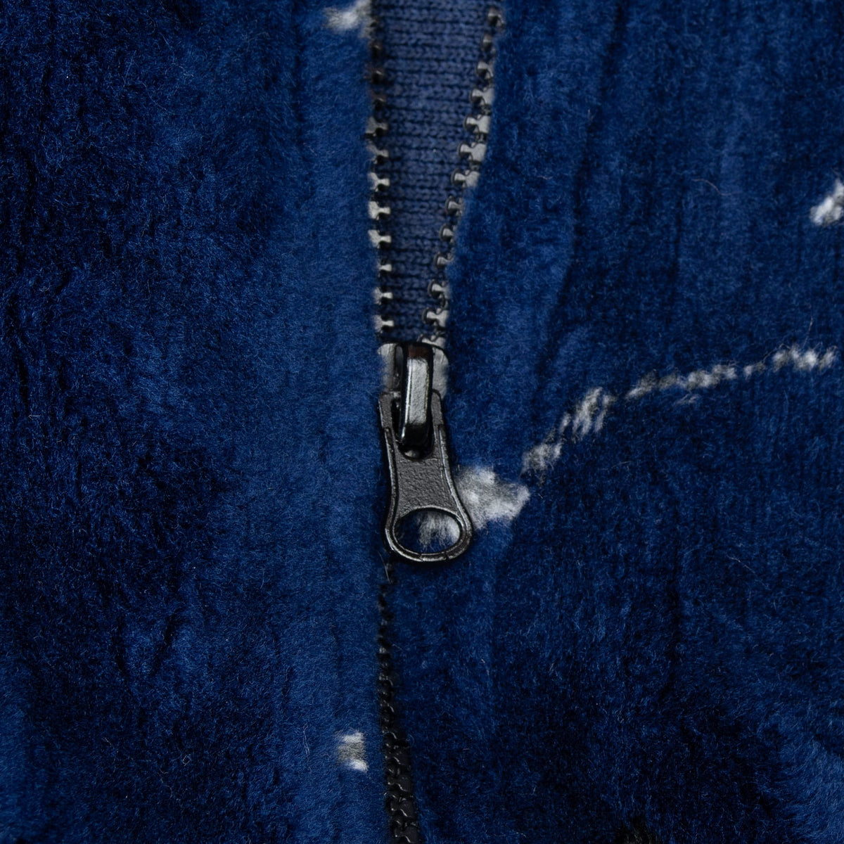 Close-up of black front zipper and plush navy fleece with white star details