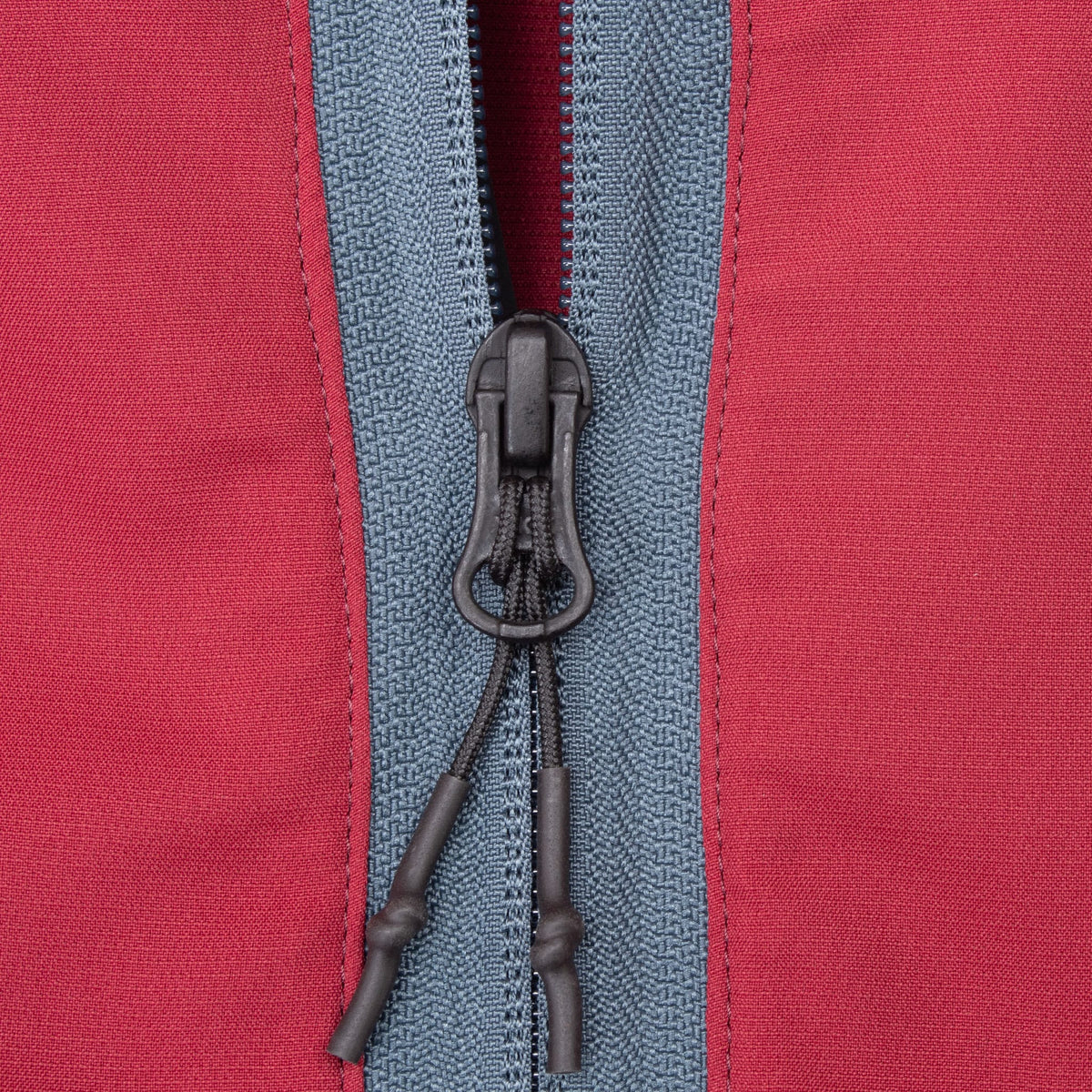 Close-up of gray half-zip closure and black corded zipper pull on burgundy Oakley windbreaker