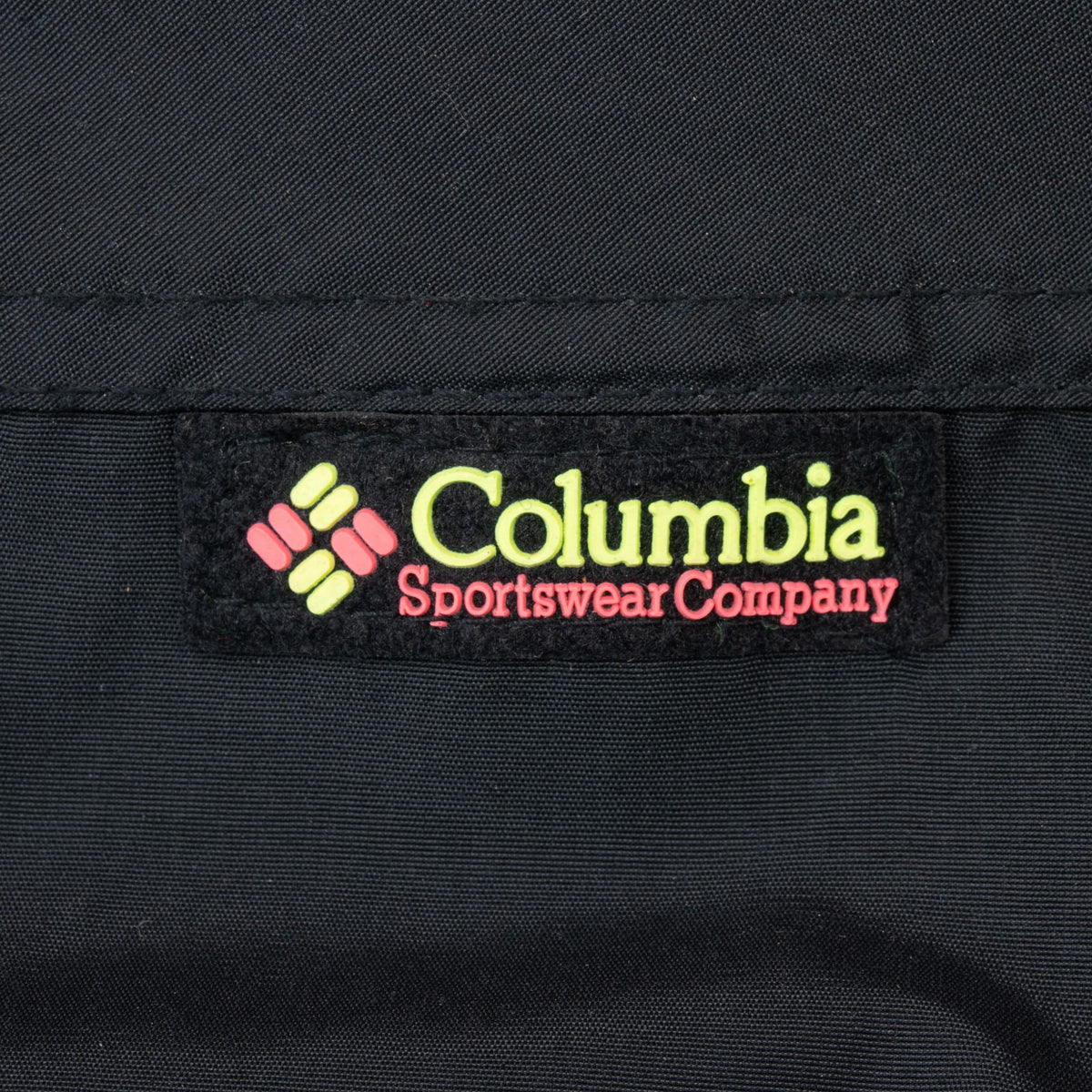 Columbia Sportswear Company chest patch in neon green and pink on black fabric