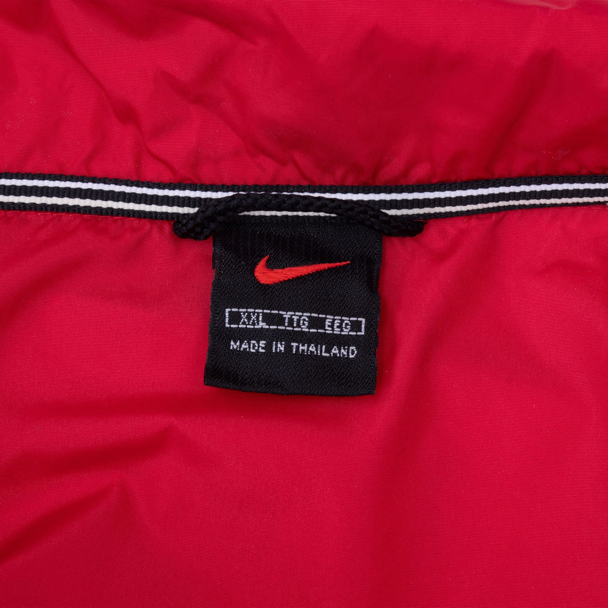 Nike neck label inside red windbreaker showing XXL sizing and Made in Thailand text