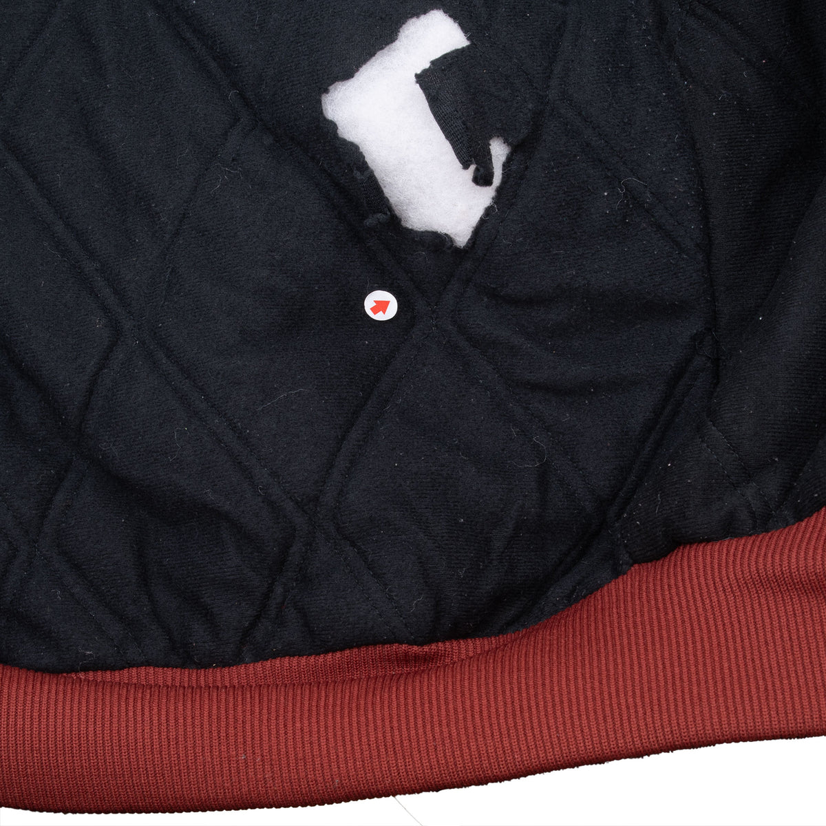 Close-up of tear in black quilted lining with white fill exposed