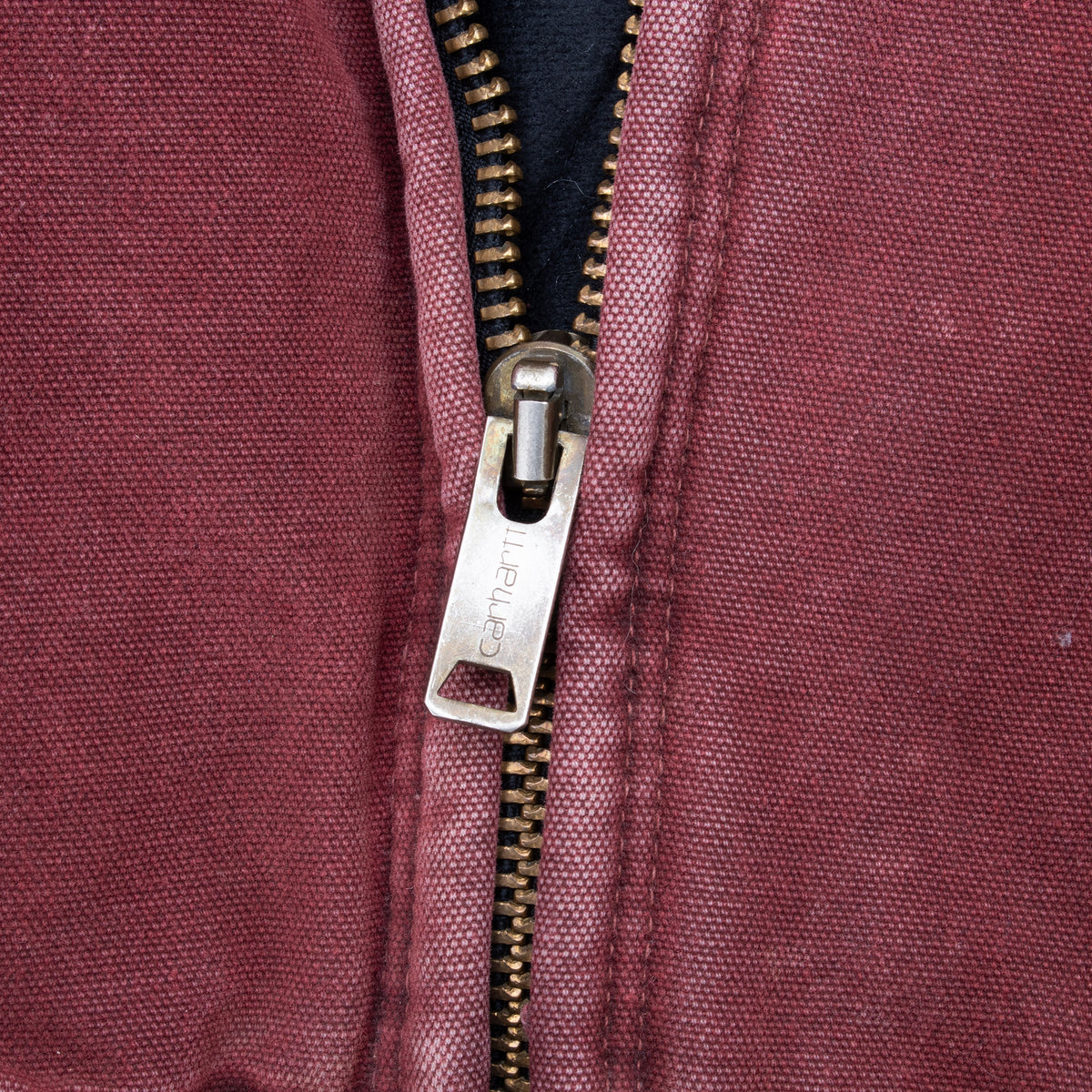 Close-up of metal Carhartt zipper on crimson red jacket
