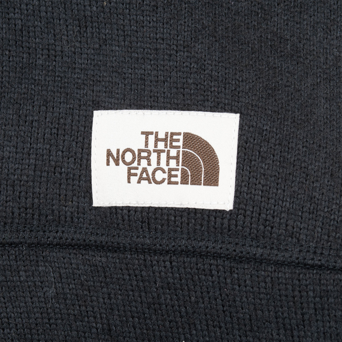Close-up of The North Face logo patch on textured black fabric