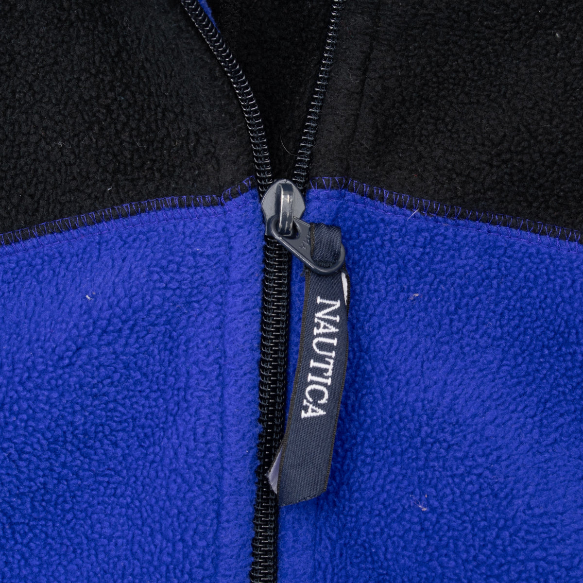Close-up of Nautica-branded quarter-zip pull and blue and black fleece fabric