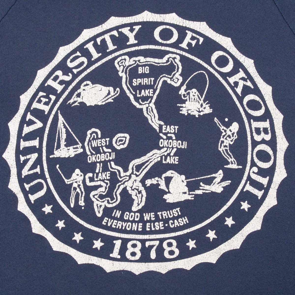Close-up of cracked white University of Okoboji seal print on navy fabric