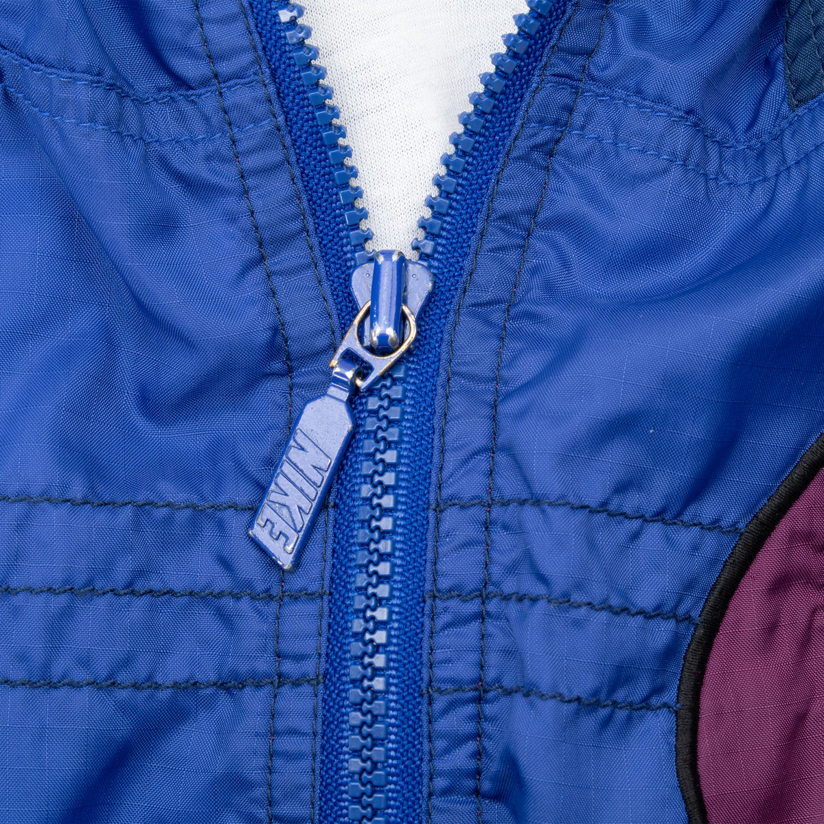 Close-up of blue Nike-branded front zipper and stitching