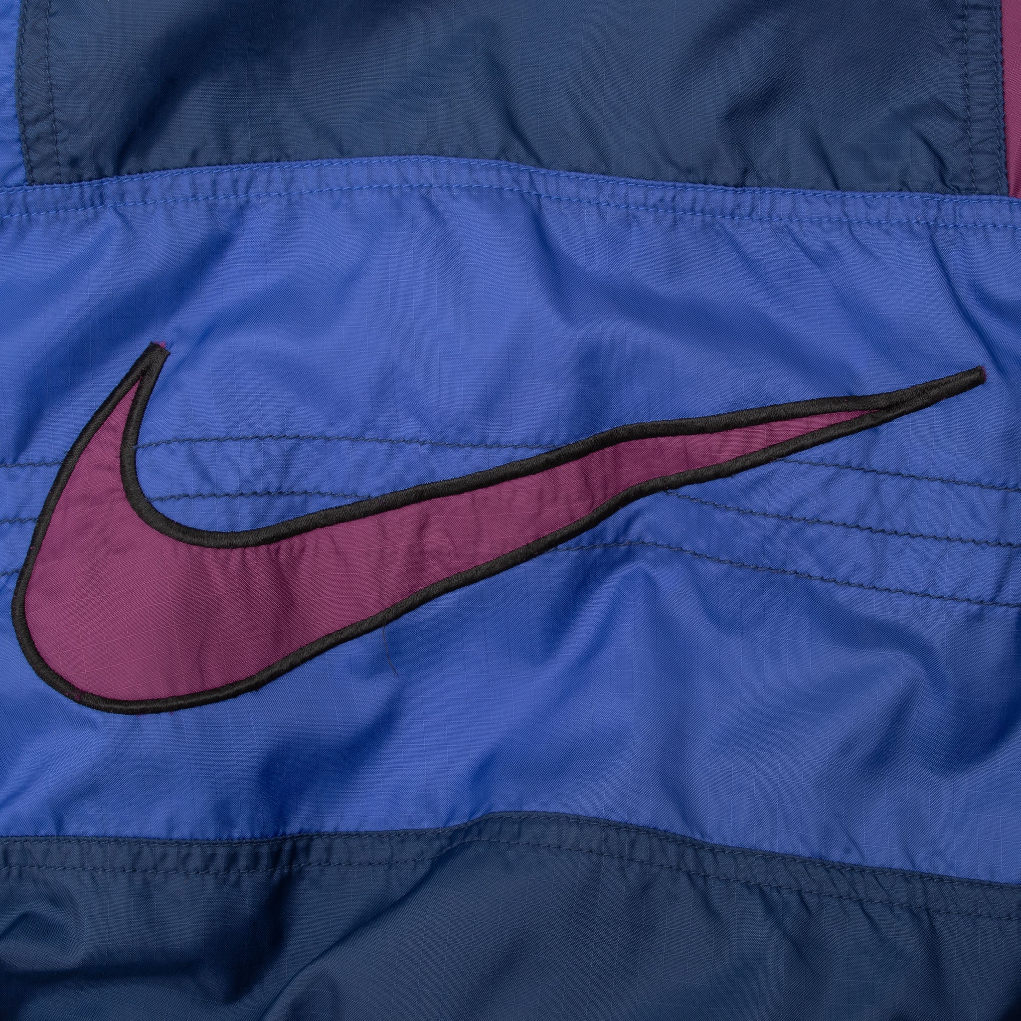 Close-up of large purple Nike Swoosh appliqué on blue front panel
