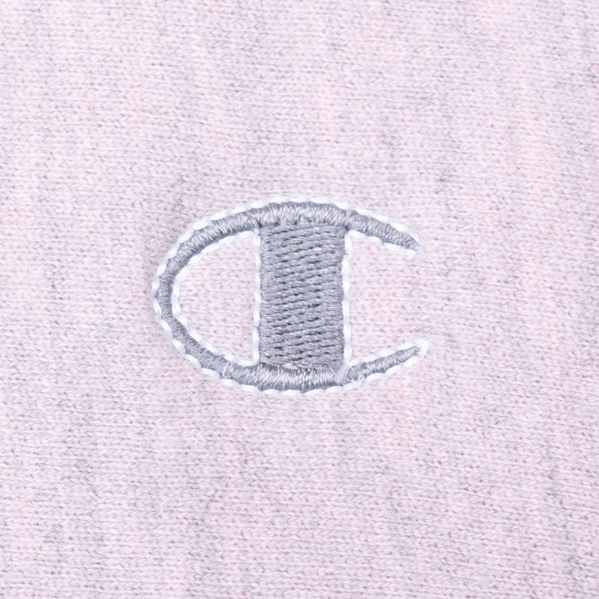 Close-up of grey embroidered Champion C logo on pink heather fabric