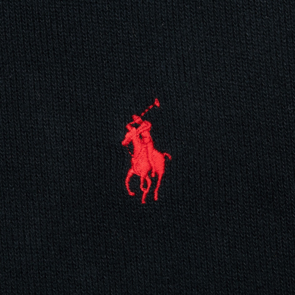 Close-up of red Polo pony embroidery on black knit fabric