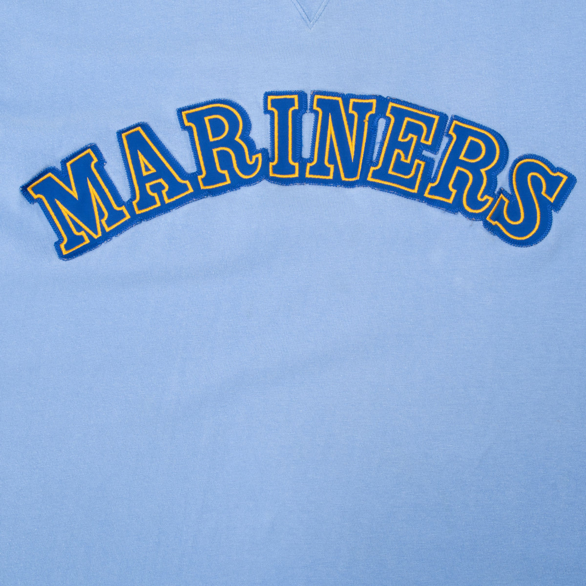 Close-up of blue and yellow embroidered Mariners lettering across the chest