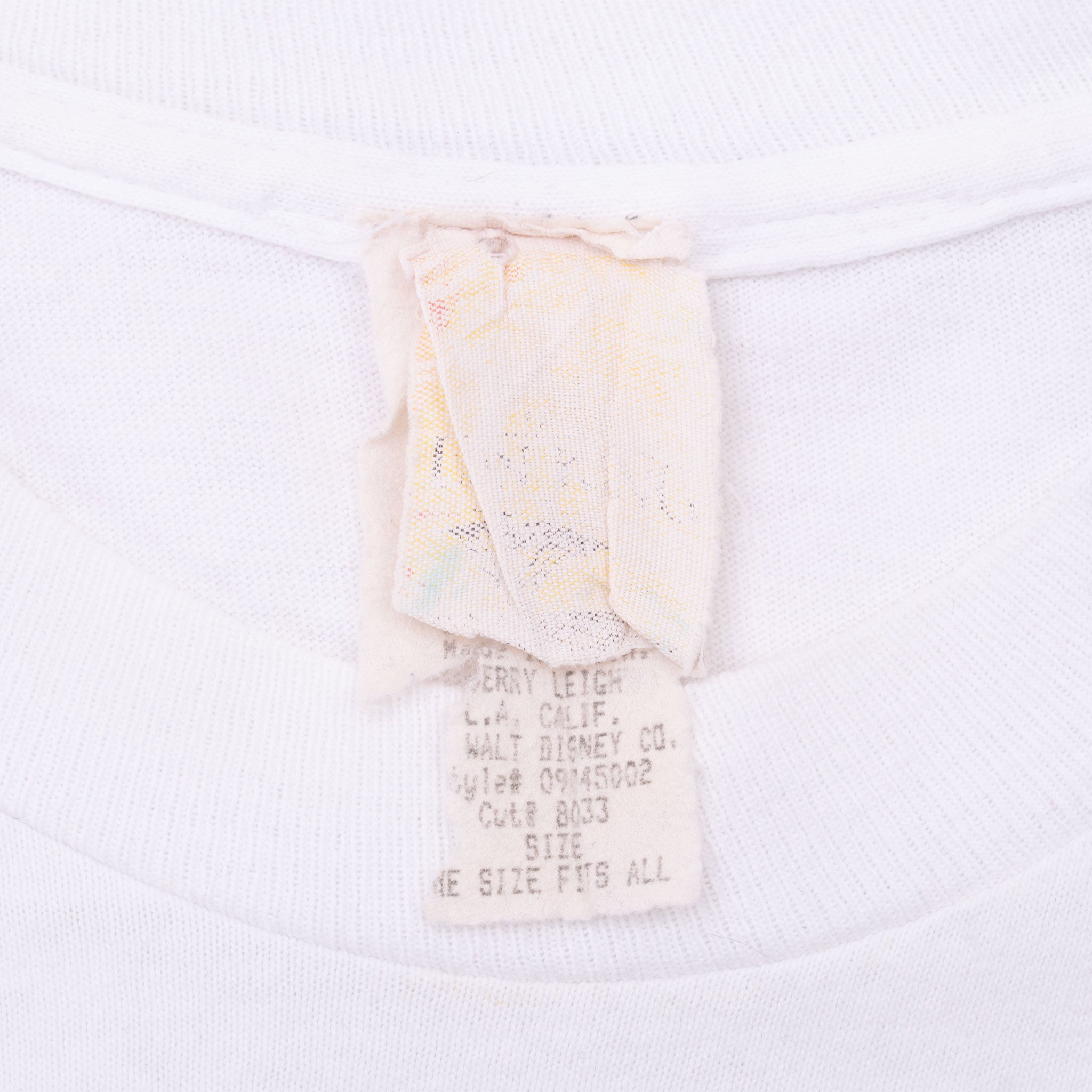 Close-up of faded neck and care labels inside white Disney The Lion King T-shirt