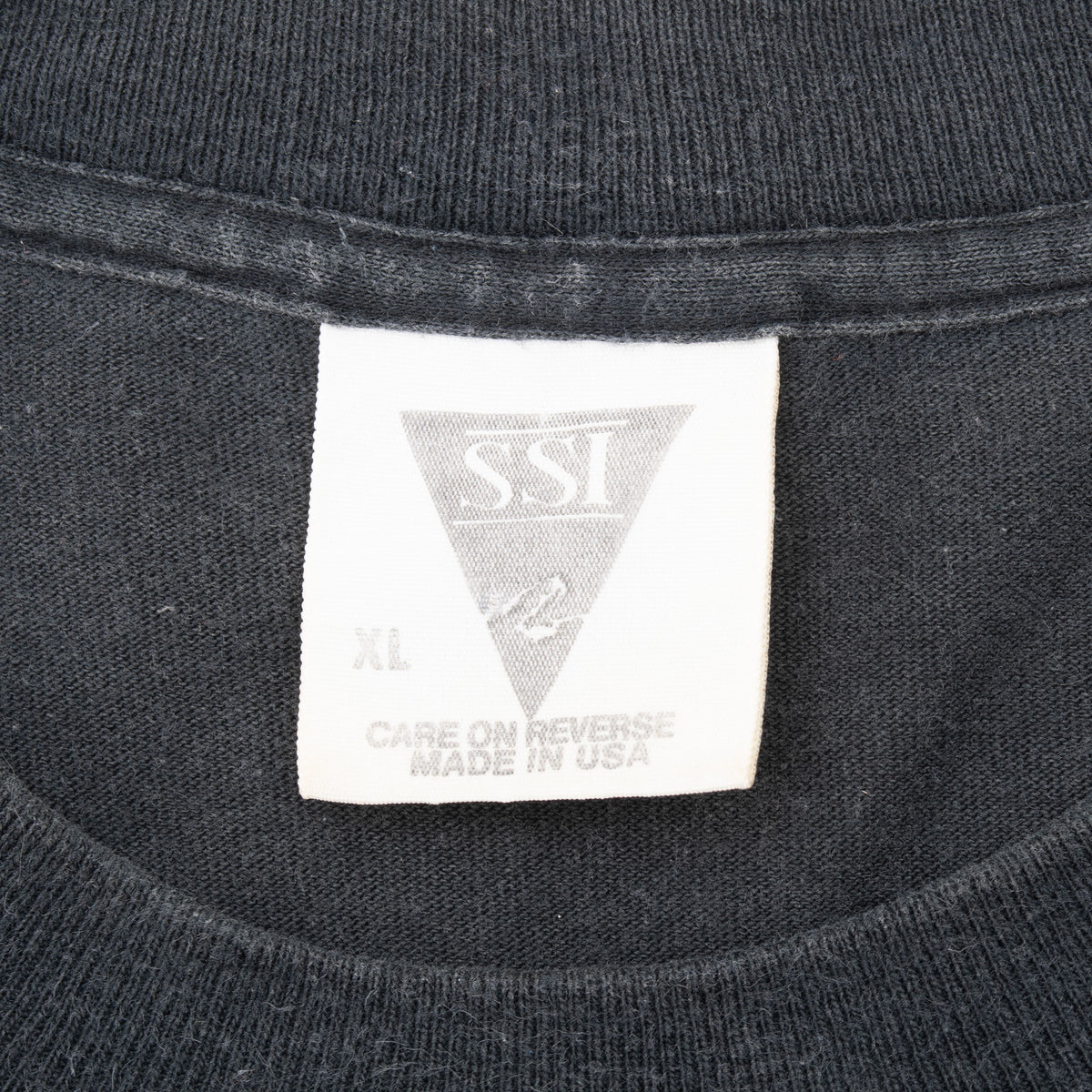 SSI XL neck tag on black T-shirt reading care on reverse and made in USA