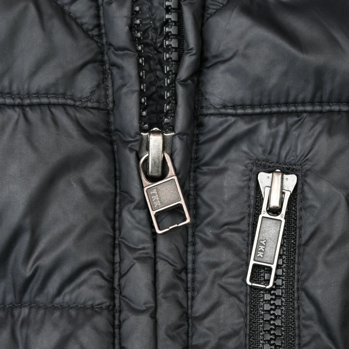 Close-up of main and chest pocket zipper pulls on black Patagonia parka