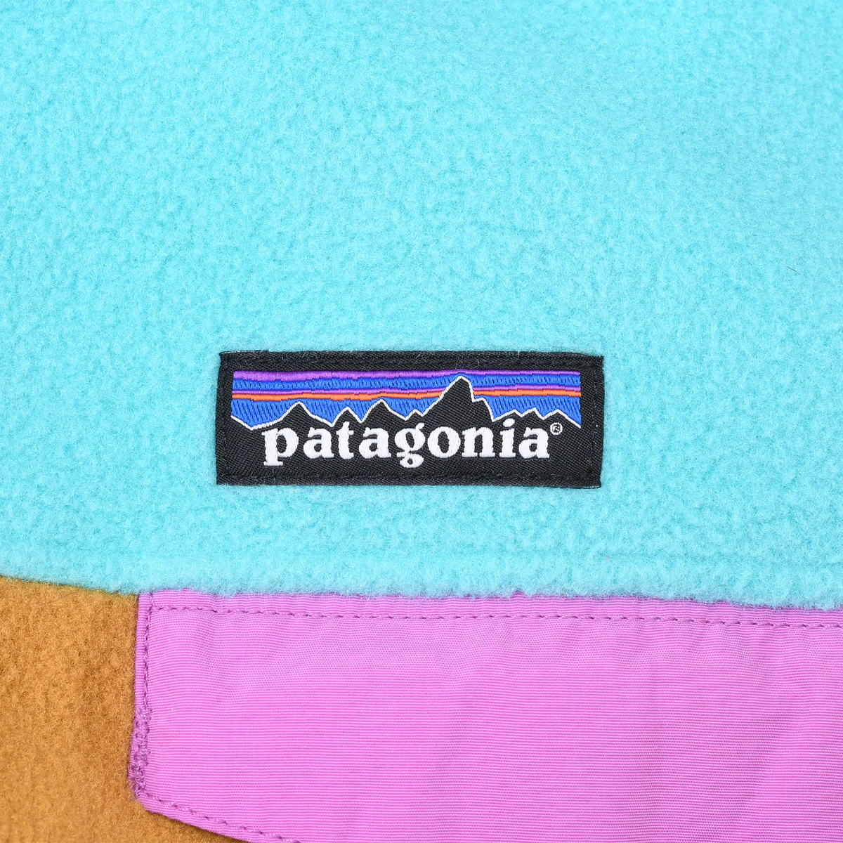 Patagonia logo patch above the pink chest pocket flap on turquoise fleece