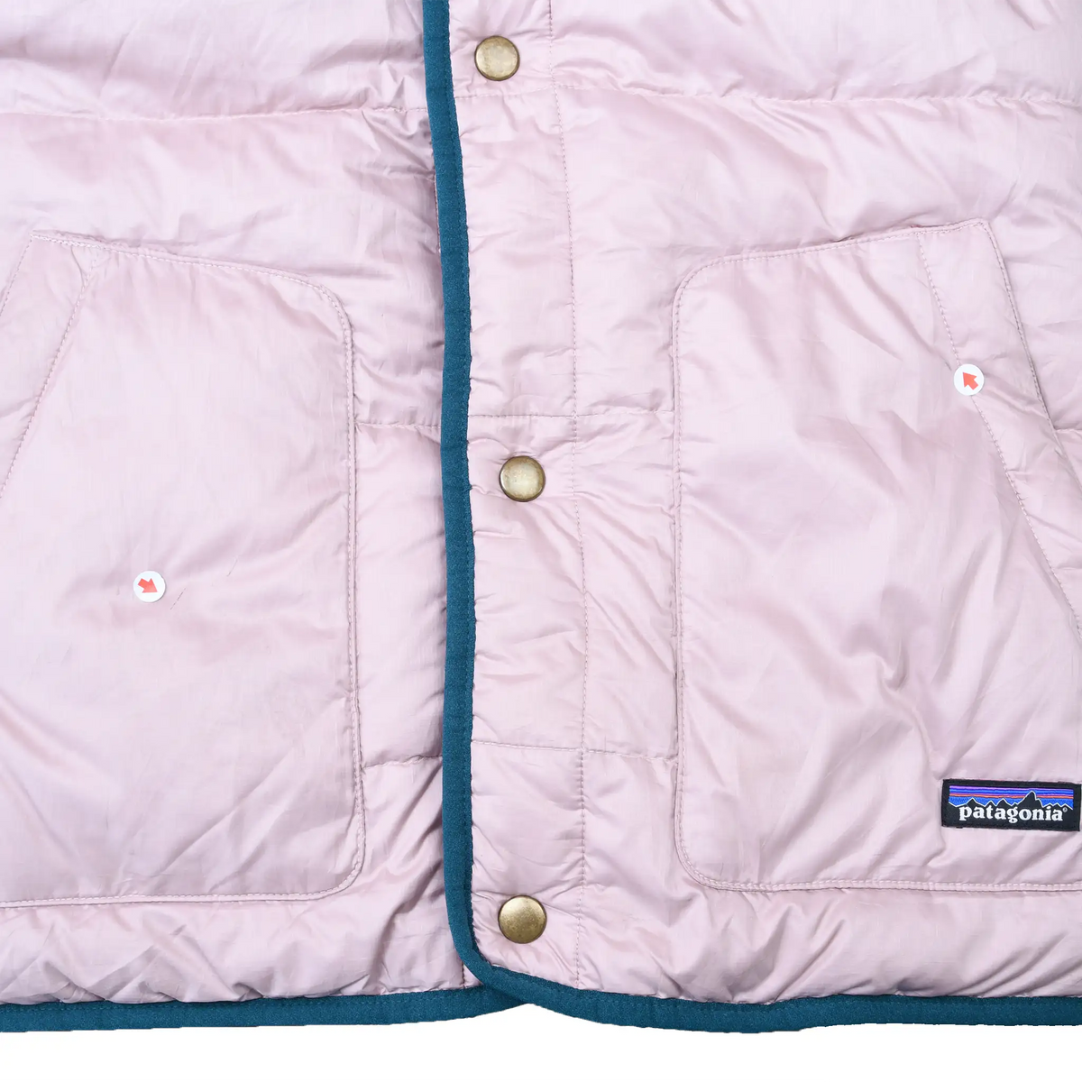 Pale pink puffer front detail with snap closure, two pockets, teal trim, and Patagonia patch