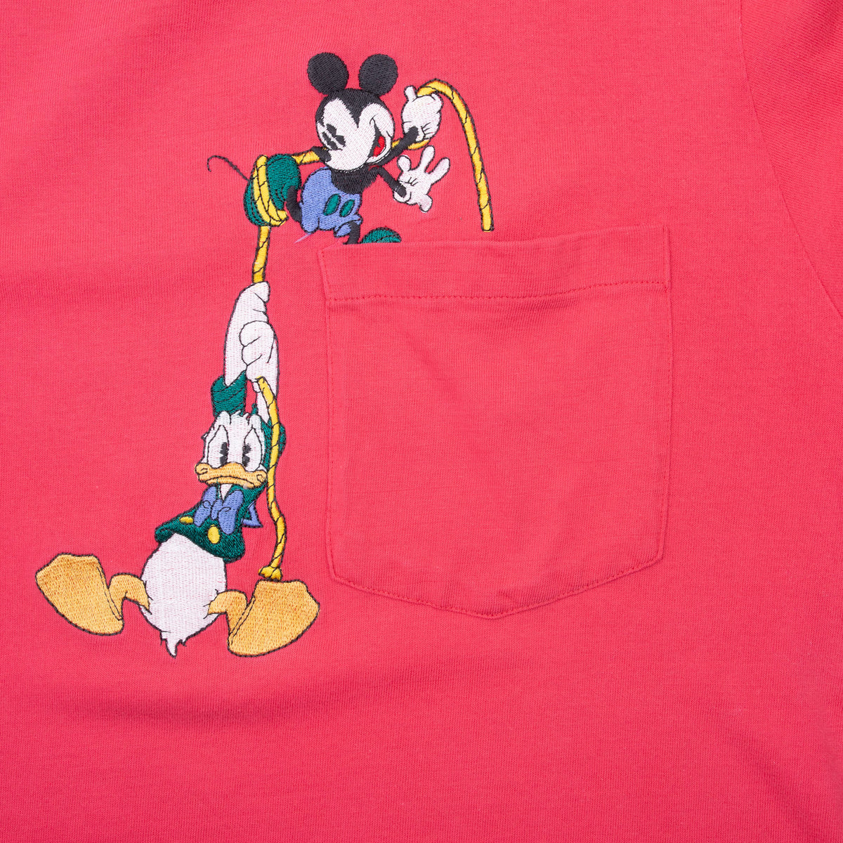 Close-up of Mickey Mouse and Donald Duck embroidery beside the chest pocket
