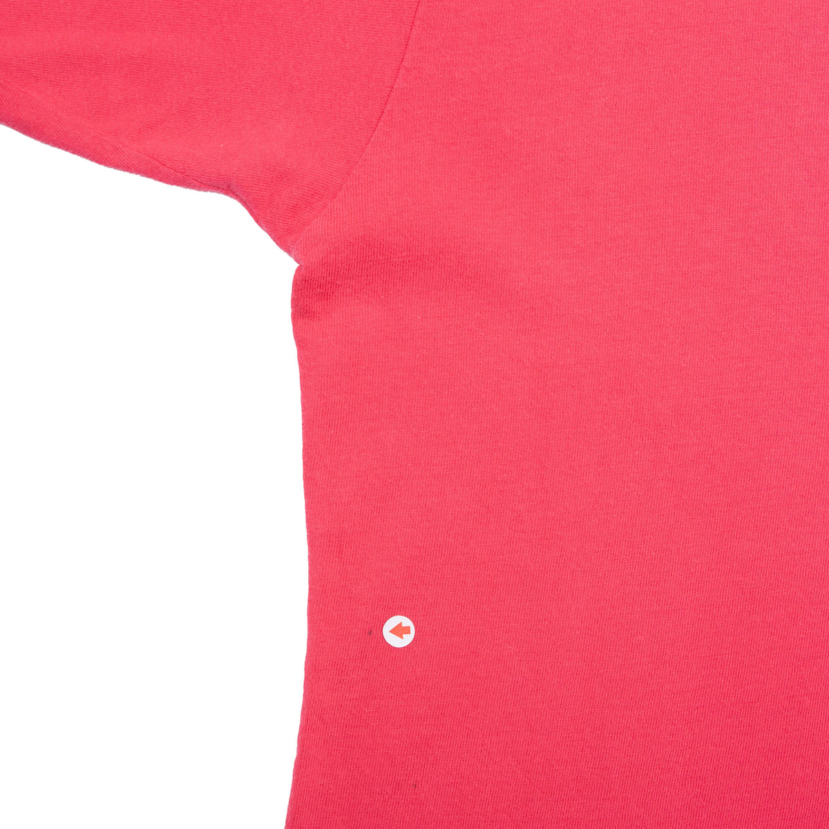 Close-up of red T-shirt underarm and side fabric with a small spot marked by an arrow