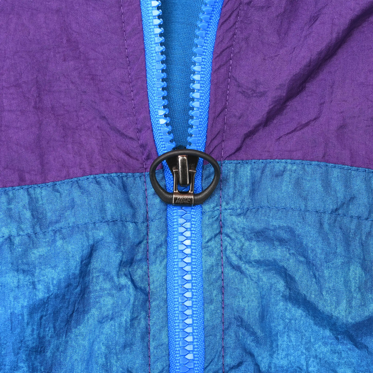 Close-up of blue front zipper with black ring pull and purple-blue color blocking