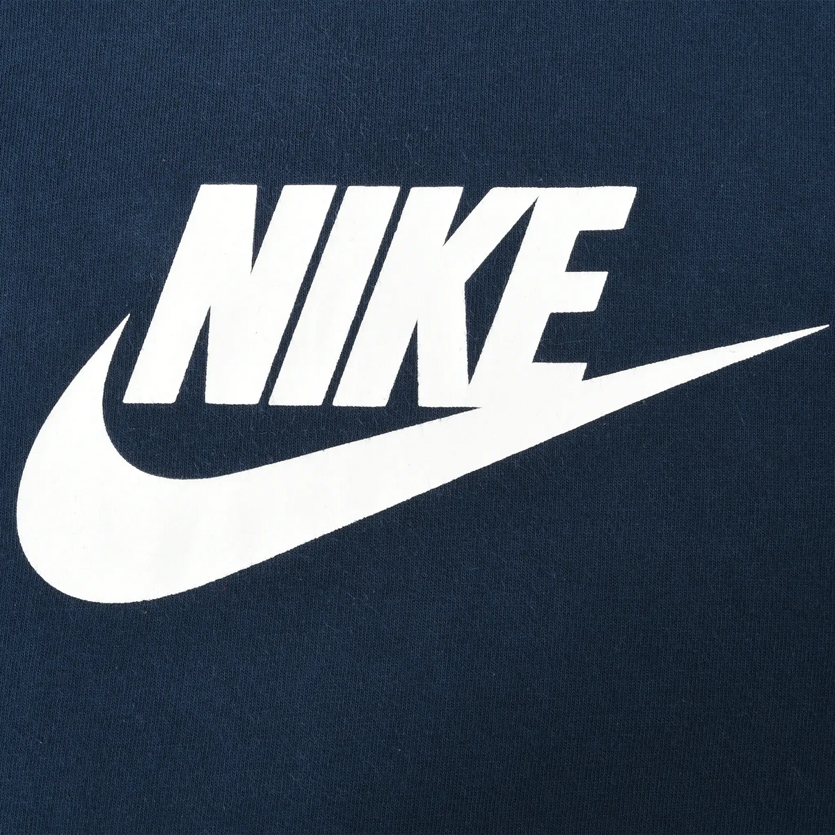 Close-up of white Nike spellout and Swoosh print on navy blue fabric