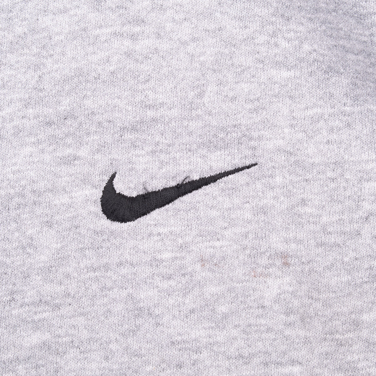 Close-up of black Nike Swoosh embroidery on grey sweatshirt