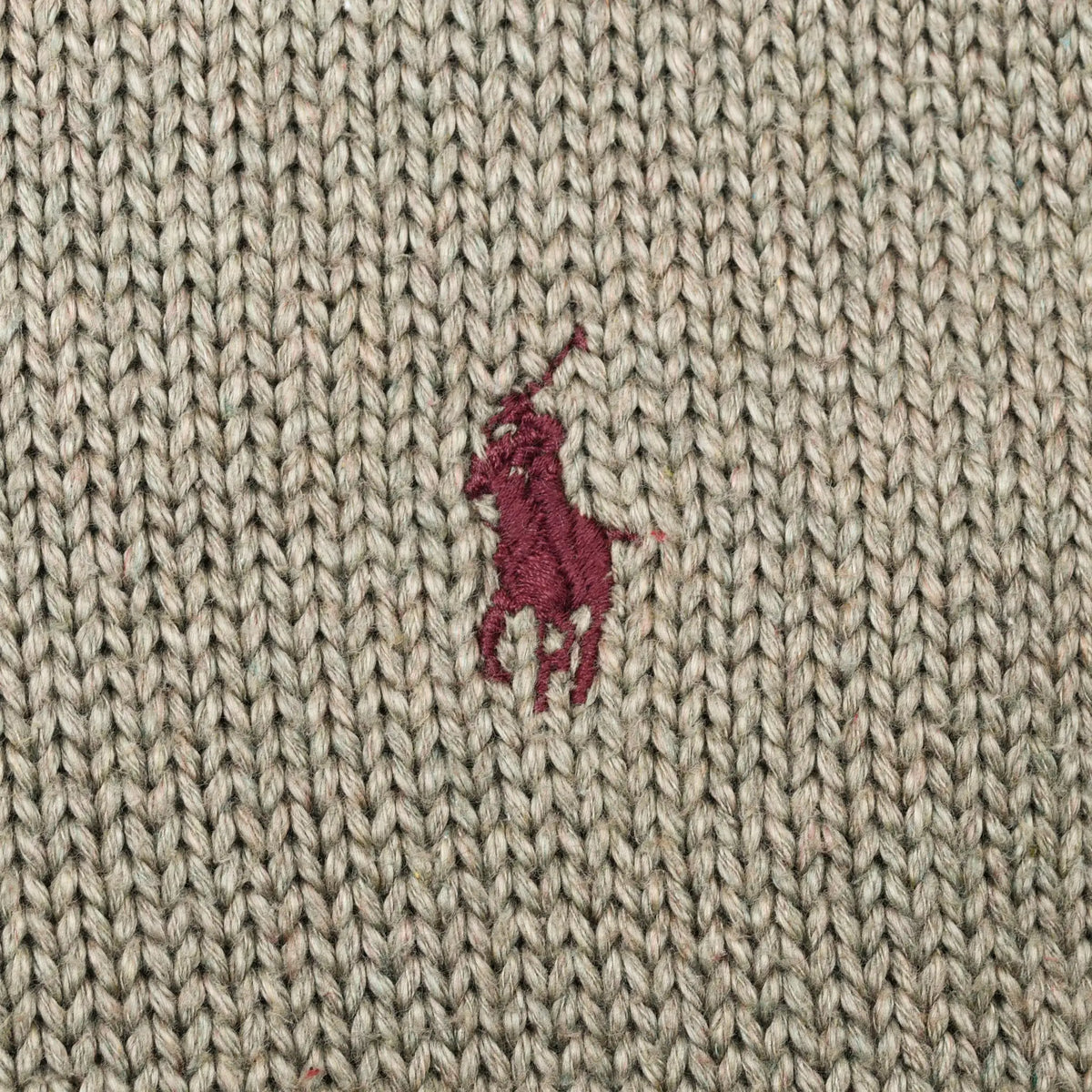 Close-up of burgundy Polo pony embroidery on sage green knit fabric