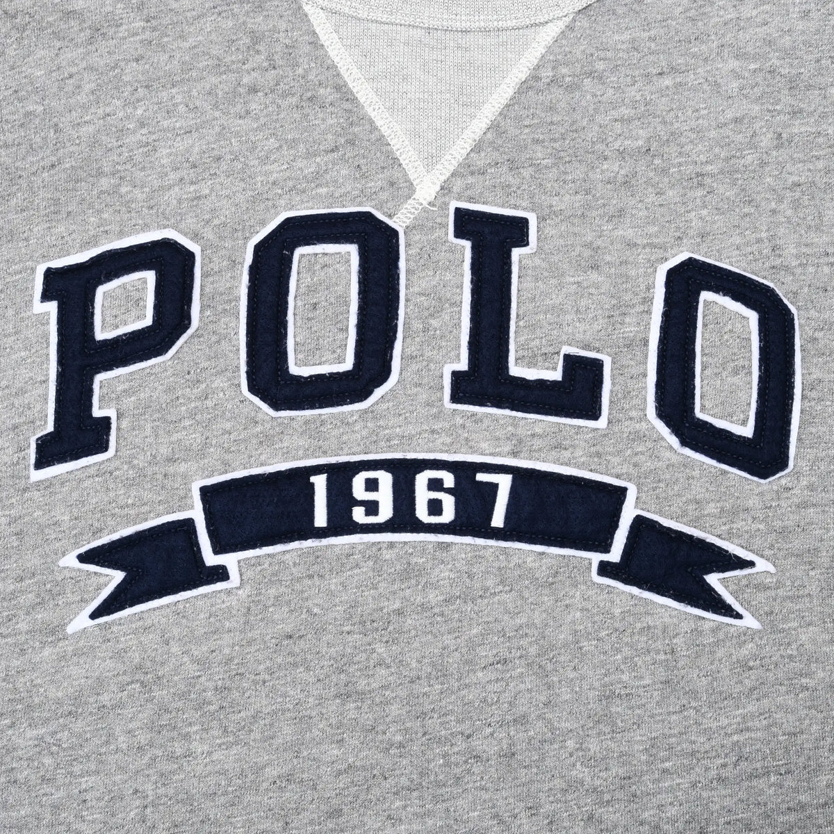 Close-up of navy and white POLO 1967 chest embroidery on grey sweatshirt