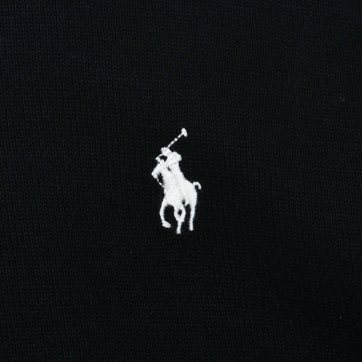 Close-up of white Polo pony embroidery on black sweater