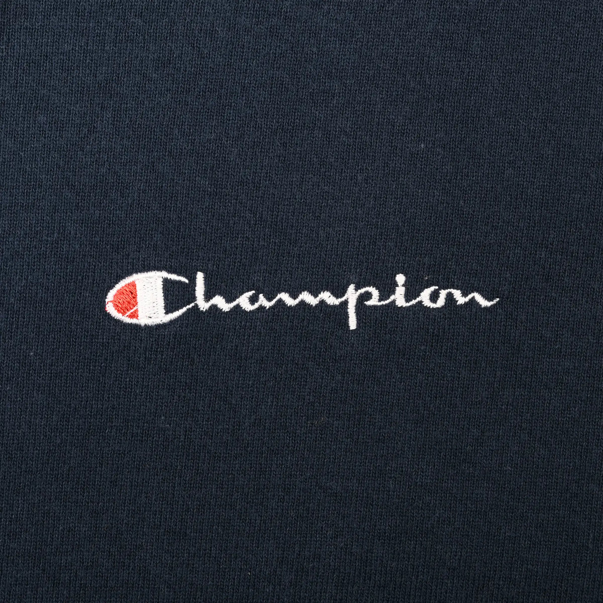 Close-up of small white, red, and blue Champion chest embroidery