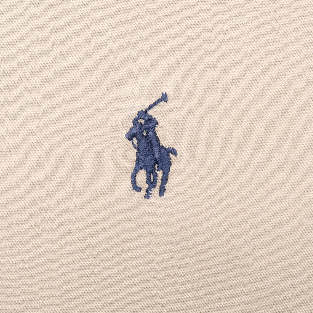 Close-up of navy Ralph Lauren Polo pony embroidery on beige fabric