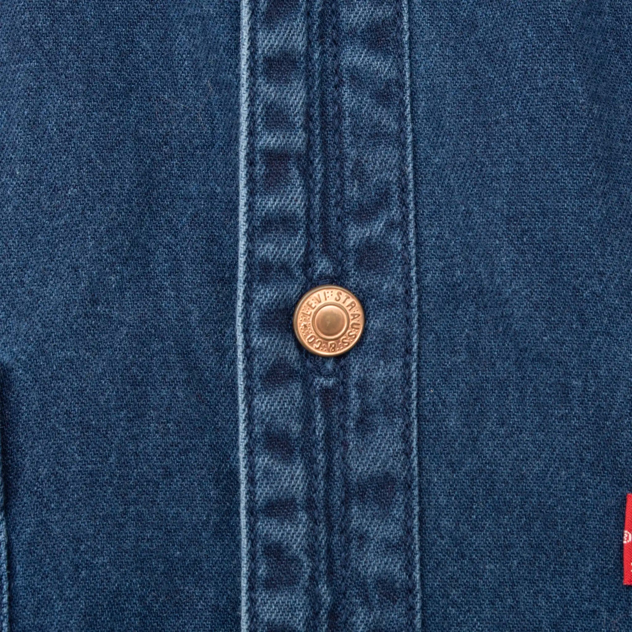 Close-up of Levi Strauss metal button on blue denim shirt placket