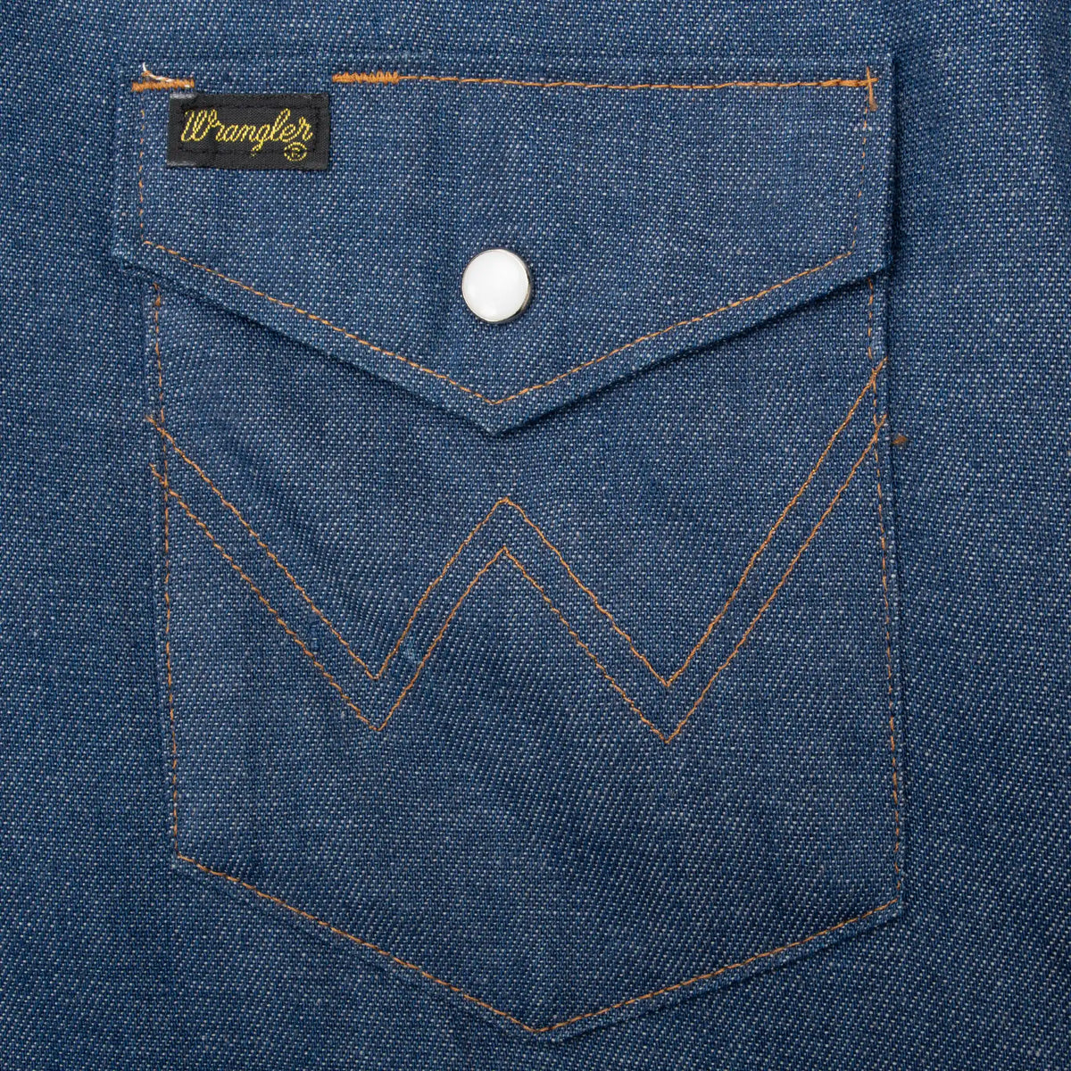 Denim chest pocket detail with Wrangler tab, pearl snap, and W stitching