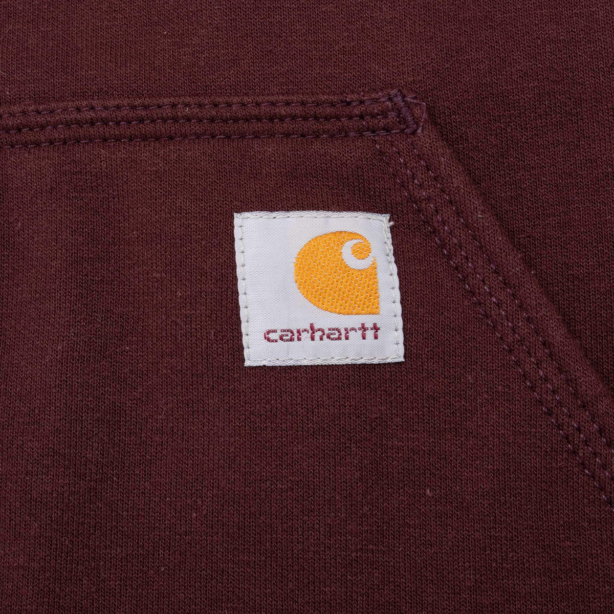 Close-up of Carhartt logo patch on burgundy kangaroo pocket