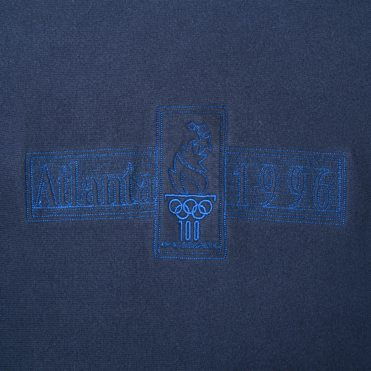 Close-up of tonal blue Atlanta 1996 Olympic Games chest embroidery