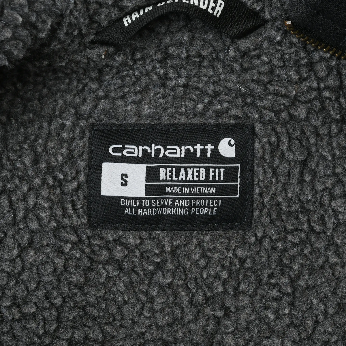 Carhartt interior label showing small size and relaxed fit against gray sherpa lining