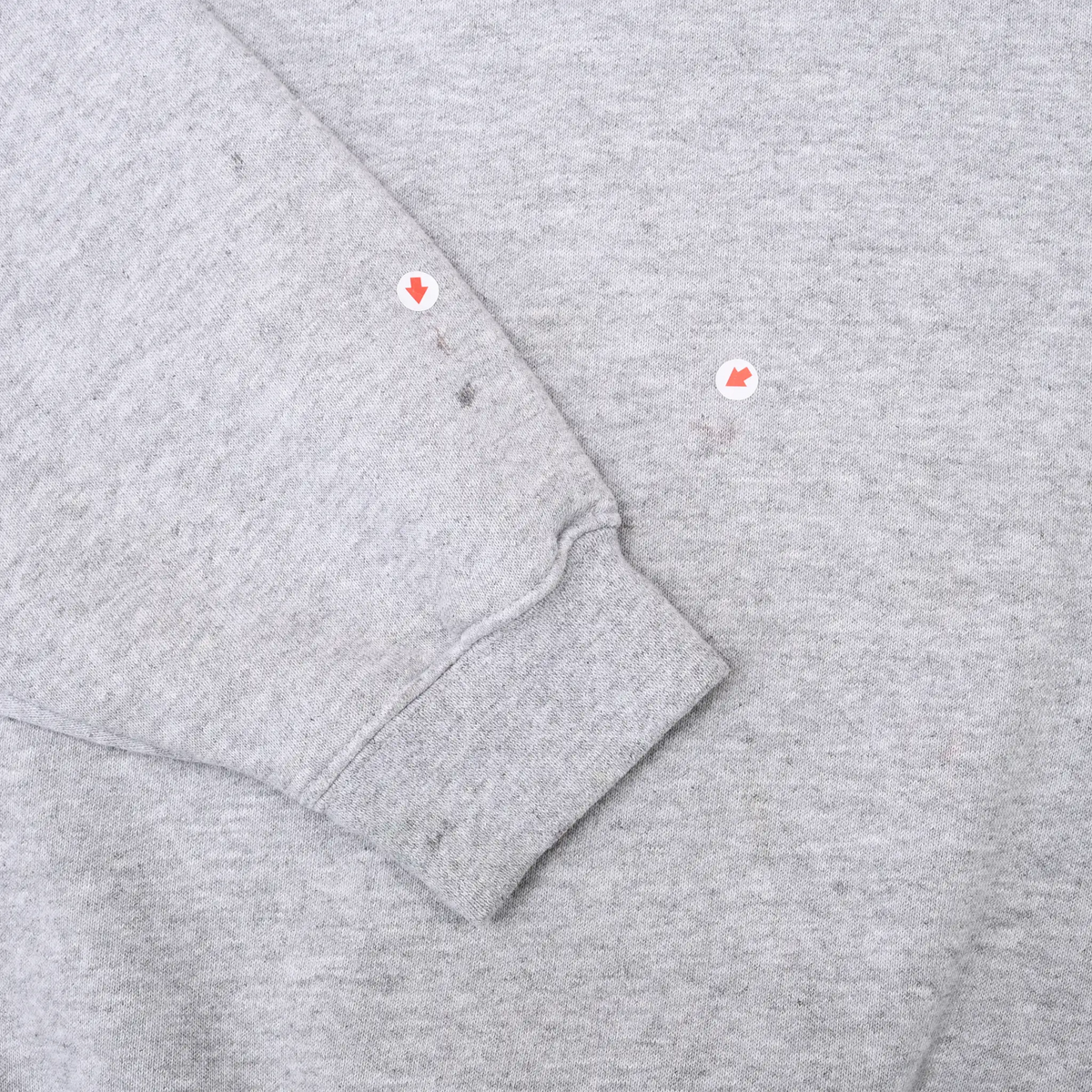 Close-up of grey sleeve cuff and small marked spots on the fabric