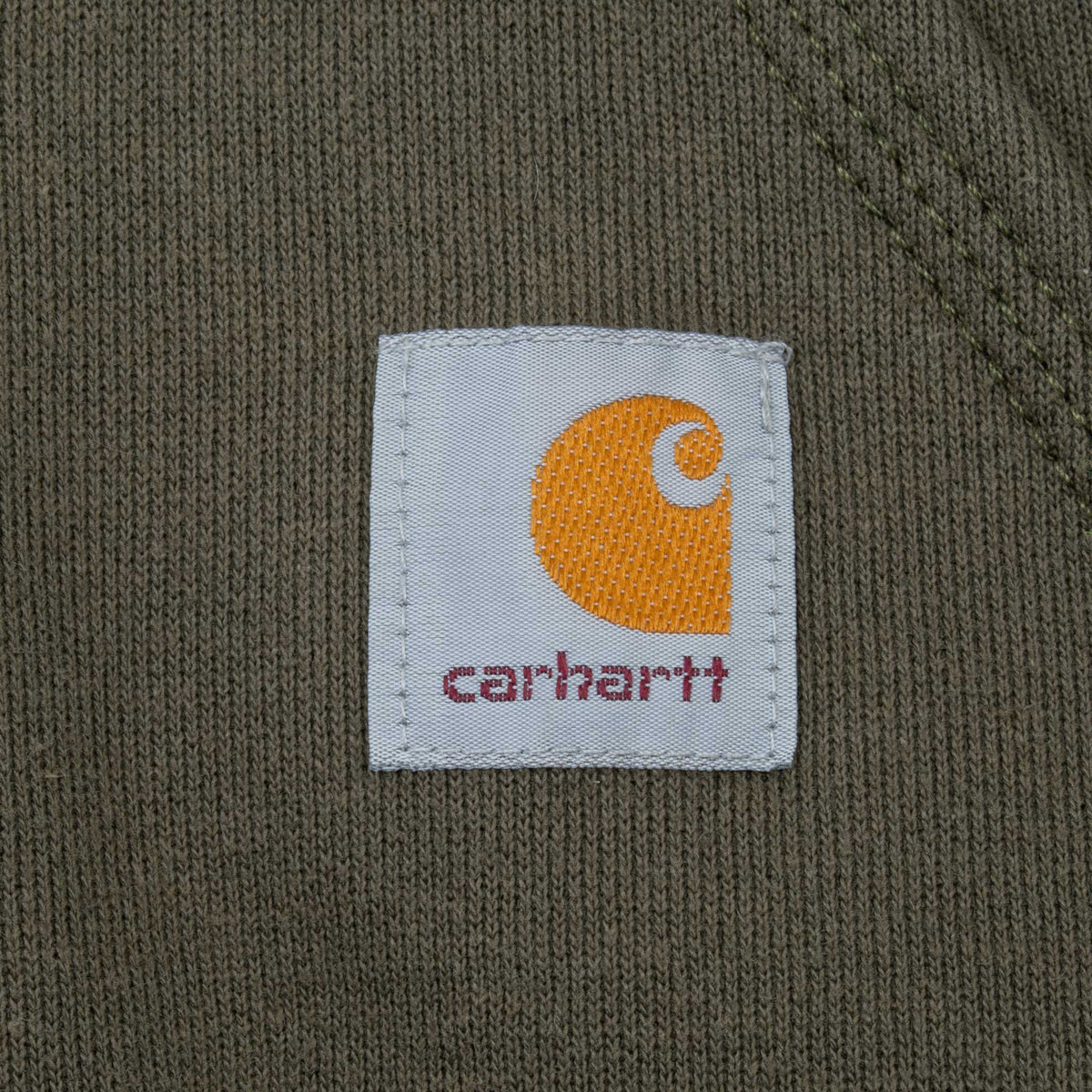 Close-up of woven Carhartt logo patch on green hoodie pocket
