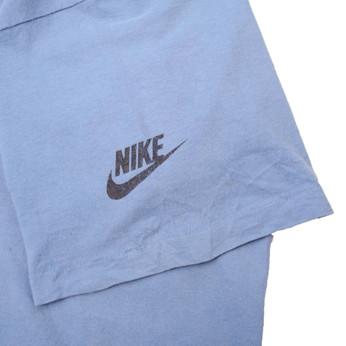 Close-up of black Nike logo printed on blue T-shirt sleeve